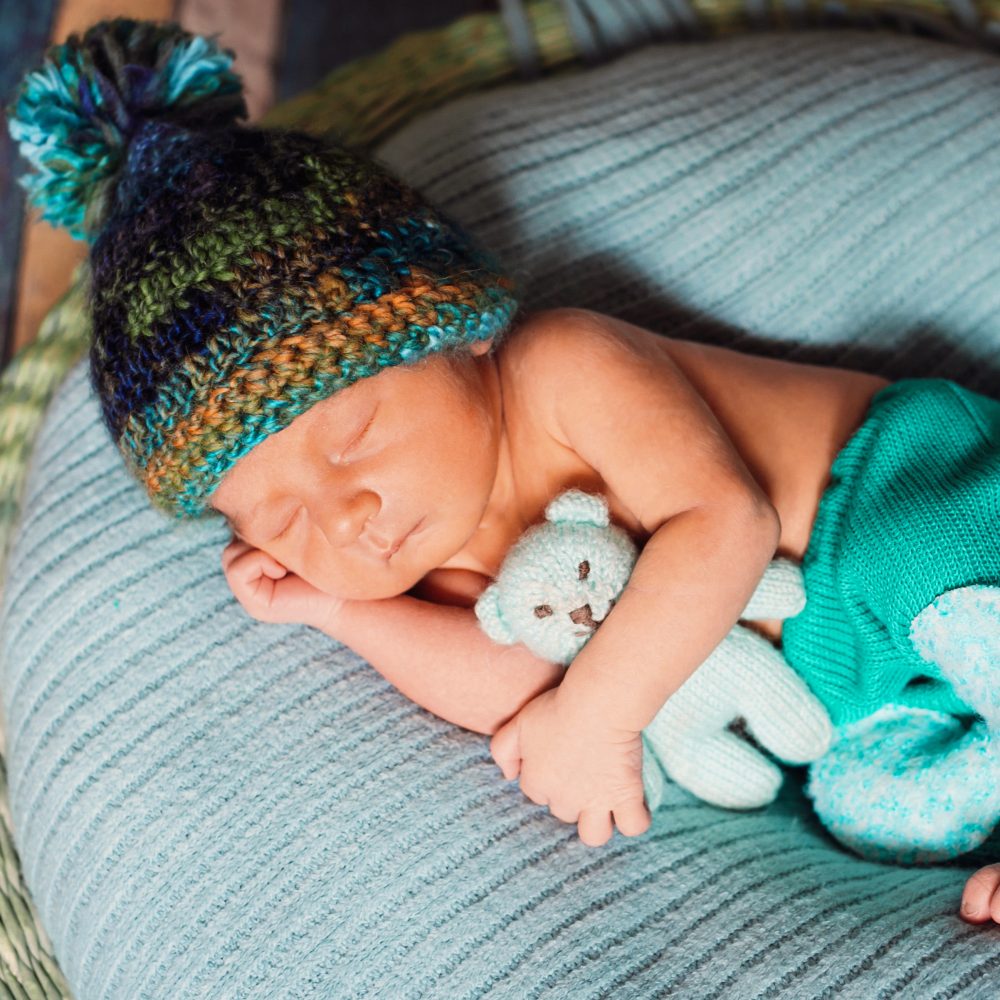 Child in knitted hat sleeps on large blue pillow
