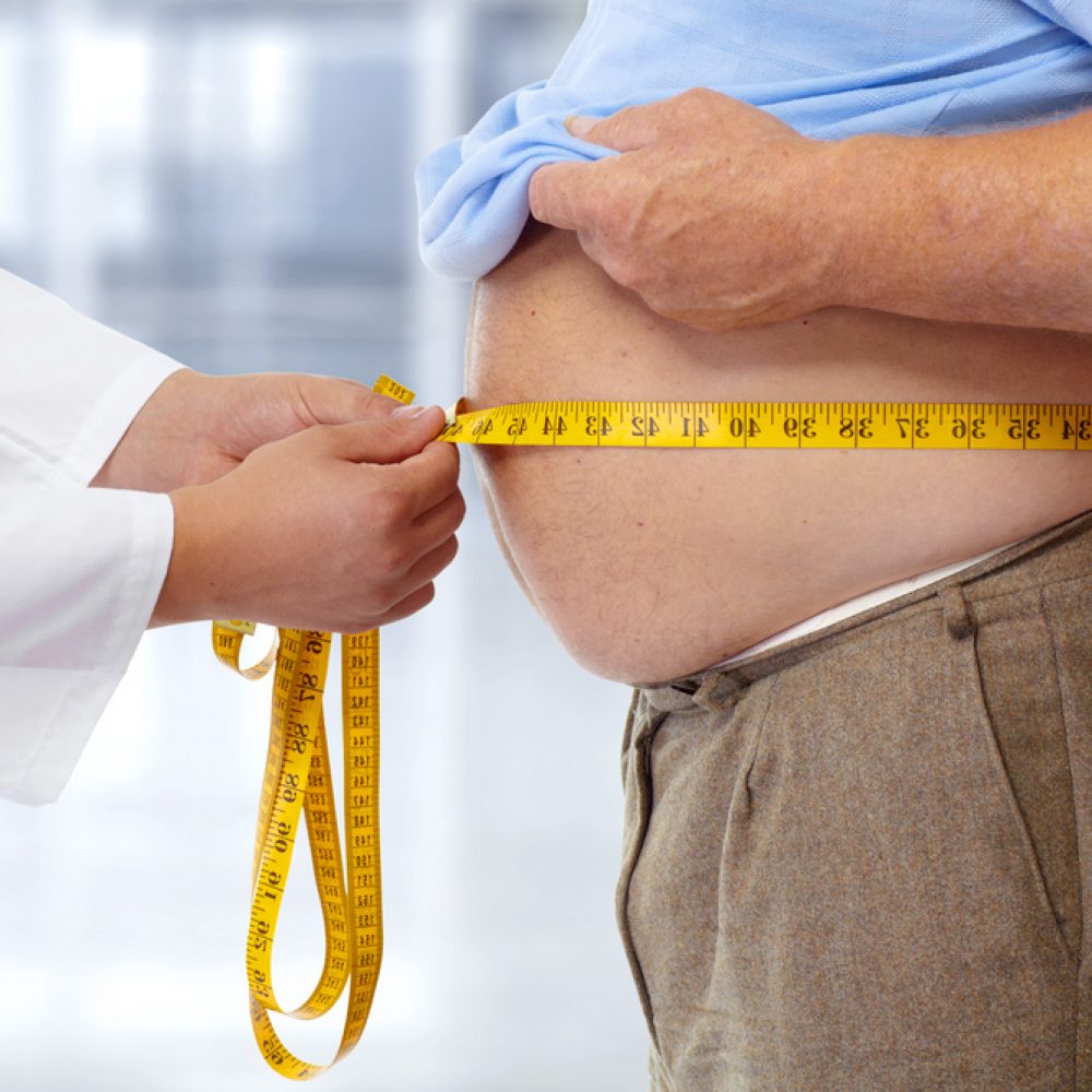 Obese boy who is overweight on a pink background.