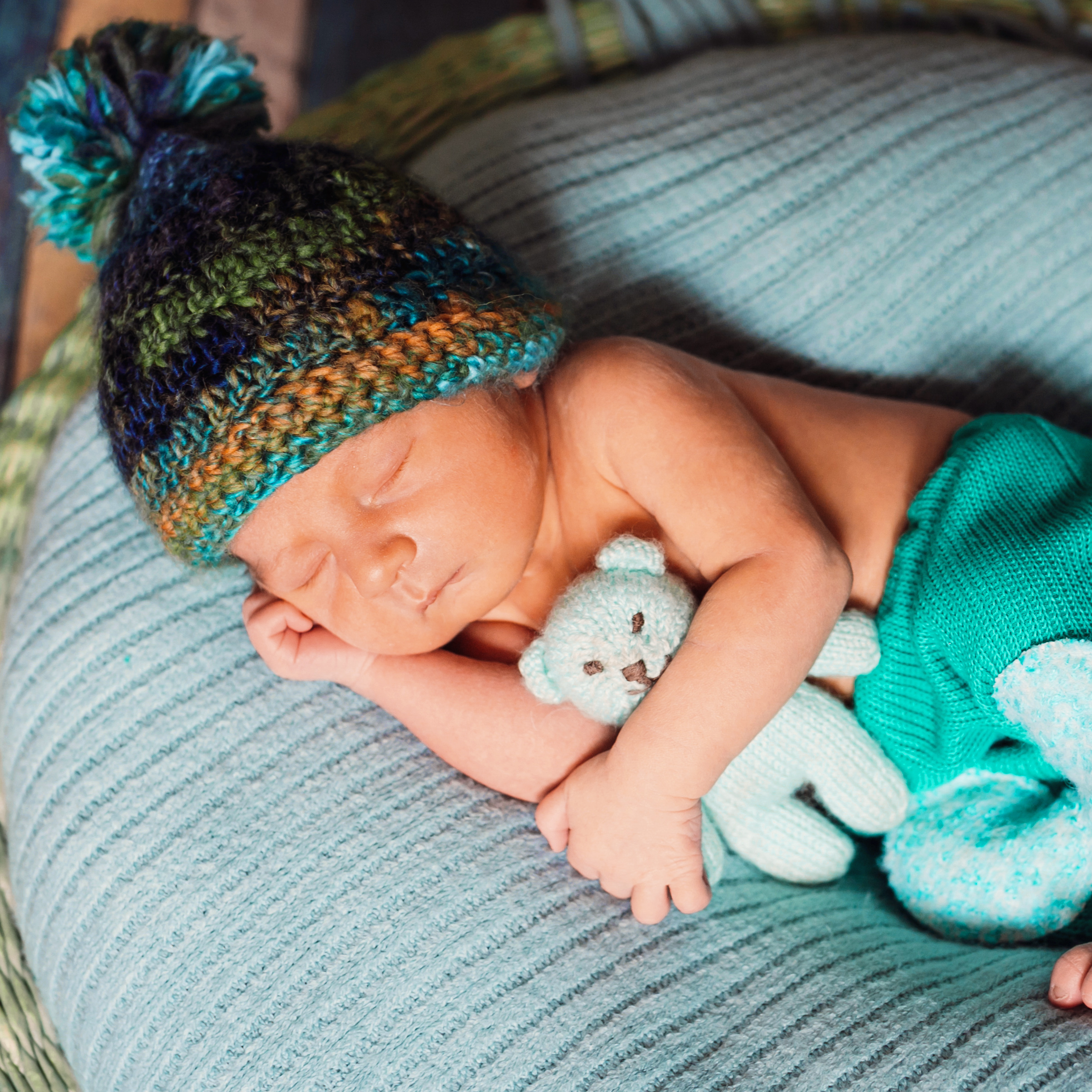 Child in knitted hat sleeps on large blue pillow
